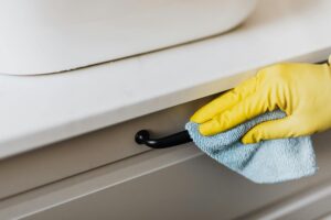 Janitorial professional disinfecting high-touch areas in an office building, including door handles, light switches, and shared workspaces for a healthier environment.